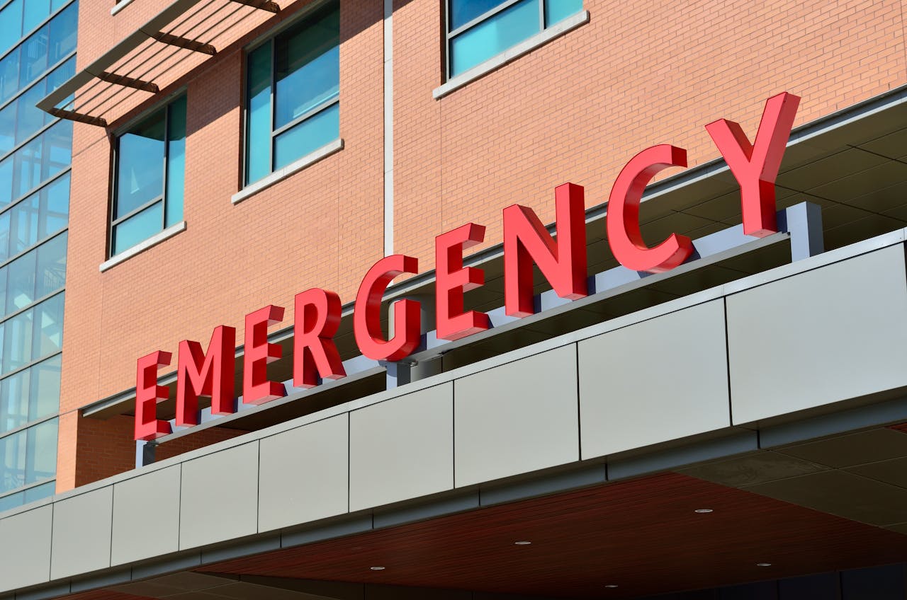 services-03 Close-up of a modern hospital emergency room entrance with prominent red letters.
